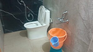 A bathroom with a toilet, a bidet, and a bucket. - Hotel O V GUEST INN  (Tenali)