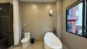 A modern bathroom with a toilet, bidet, and bathtub.