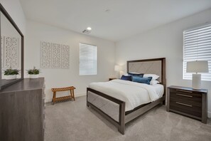 A bedroom with a bed, bedside tables, a bench, and decorative wall panels. - The Reserve | Modern 5BR Henderson Pool Home (Henderson)