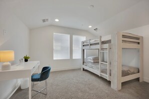 A child's bedroom with bunk beds, a desk, a chair, and a lamp. - The Reserve | Modern 5BR Henderson Pool Home (Henderson)