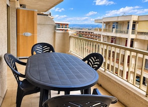 A balcony with a round table and four chairs, overlooking a residential area with buildings and a clear sky. - Yamila (Salou)