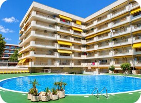 Un edificio de varios pisos con una piscina al frente.