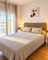 Habitación de hotel con una cama grande, una mesita de noche con lámpara, una obra de arte en la pared y vistas al exterior.
