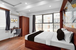 A modern bedroom with a large bed, a desk, and a chair. - Townhouse Whitefield Railway Station (Bangalore)