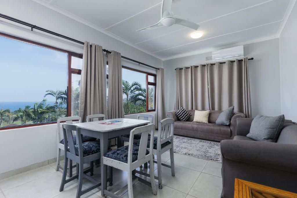 Une pièce comprenant une table à manger, des chaises, un canapé et un ventilateur de plafond.