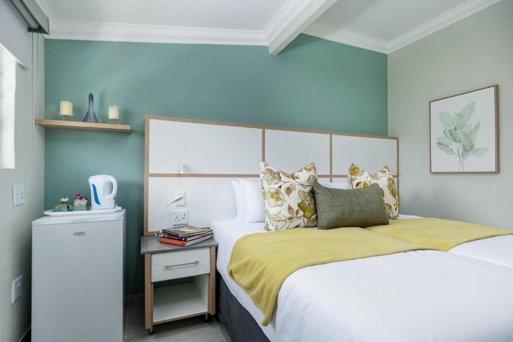 Una habitación de hotel con cama, mesita de noche y una pequeña cocina.