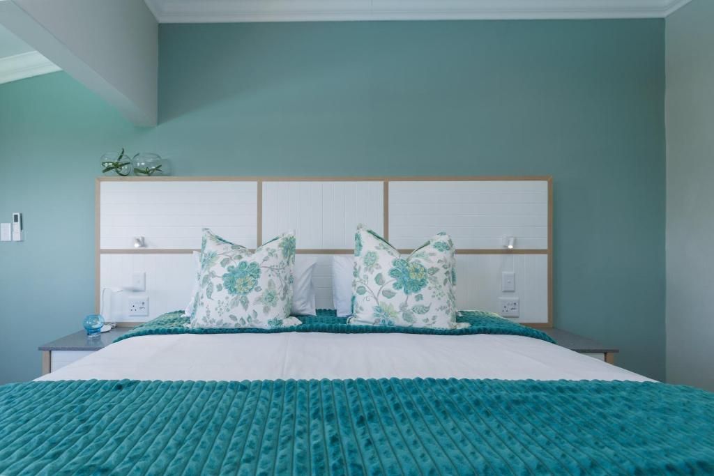 A bedroom with a bed, a nightstand, and a wall-mounted shelf with decorative items.
