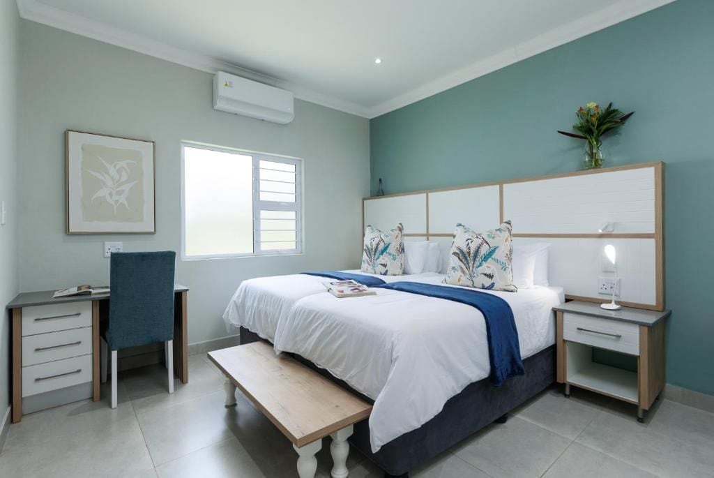 A bedroom with a bed, bedside tables, a desk, a chair, and a window.