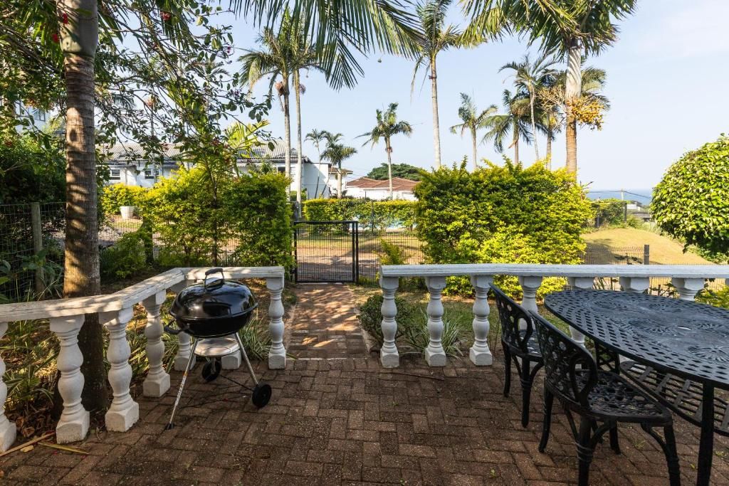 A patio with a grill, seating, and a view of a residential area with palm trees.