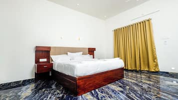 Quarto de hotel com cama de madeira, mesa de cabeceira, luminária na parede e cortina.