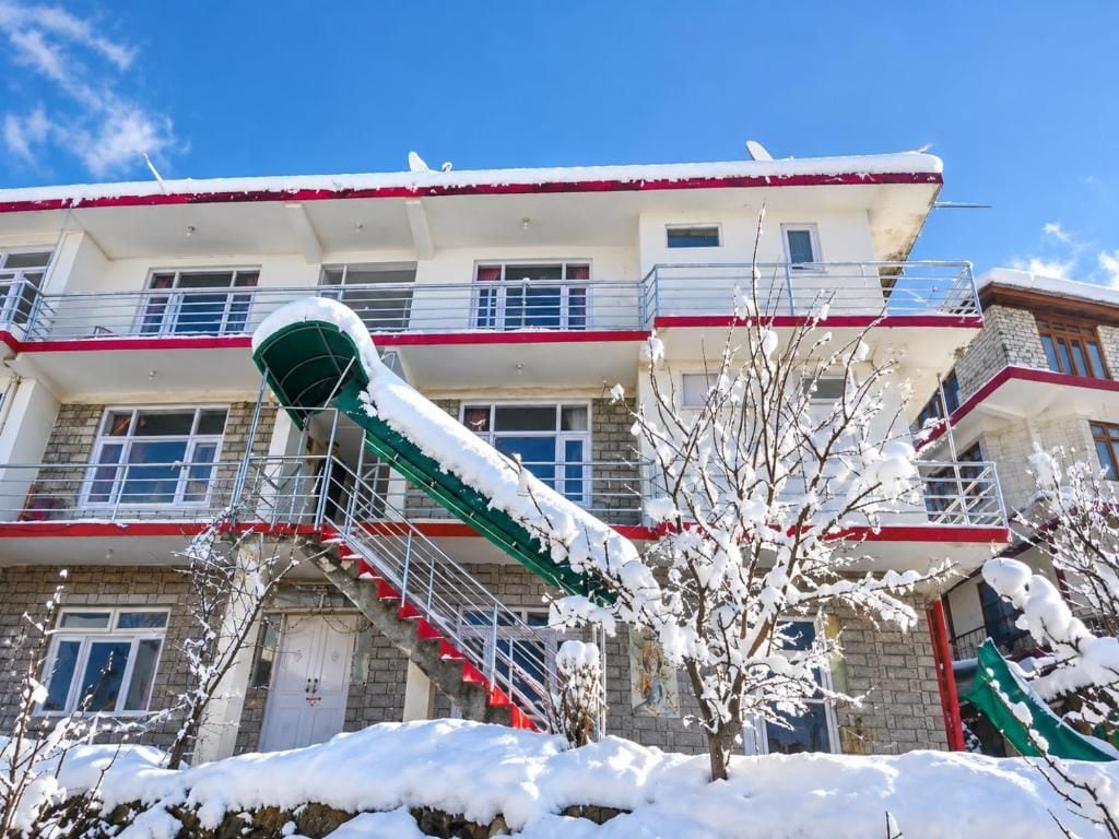 A multi-story building with a red and white facade, a staircase, and snow-covered trees.