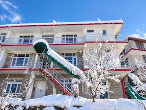 A multi-story building with a red and white facade, a staircase, and snow-covered trees.