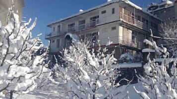 Un immeuble à étages, doté de balcons et dont le sol est recouvert de neige.