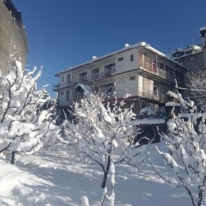 Un edificio de varios pisos con balcones y un terreno cubierto de nieve.