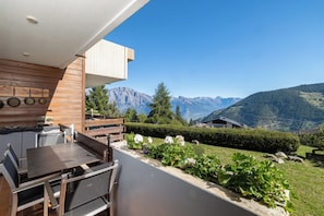 Una cocina moderna al aire libre con comedor y vistas a un paisaje montañoso.