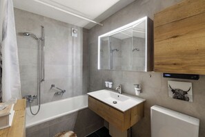 A modern bathroom with a shower, a sink, and a mirror. - App. La Forêt 43 (Riddes)