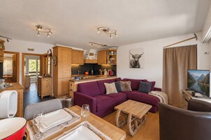 Una sala acogedora con un sofá púrpura, una mesa de centro de madera y un televisor.