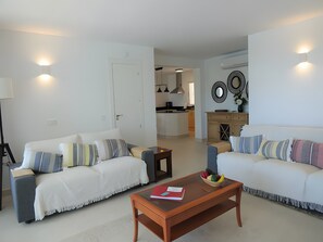 A living room with two sofas, a coffee table, and a kitchen in the background. - Apartment 'Residencia La Fuente' with Shared Pool, Wi-Fi and Air Conditioning (Mijas)
