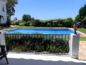A swimming pool with a metal railing, surrounded by greenery and a clear sky. - Apartment 'Residencia La Fuente' with Shared Pool, Wi-Fi and Air Conditioning (Mijas)