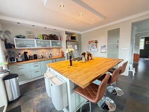 A modern kitchen with a wooden island, bar stools, and a refrigerator. - Family Friendly House by Laugardalur Park & Pool, 2.5. km from Downtown (Reykjavík)