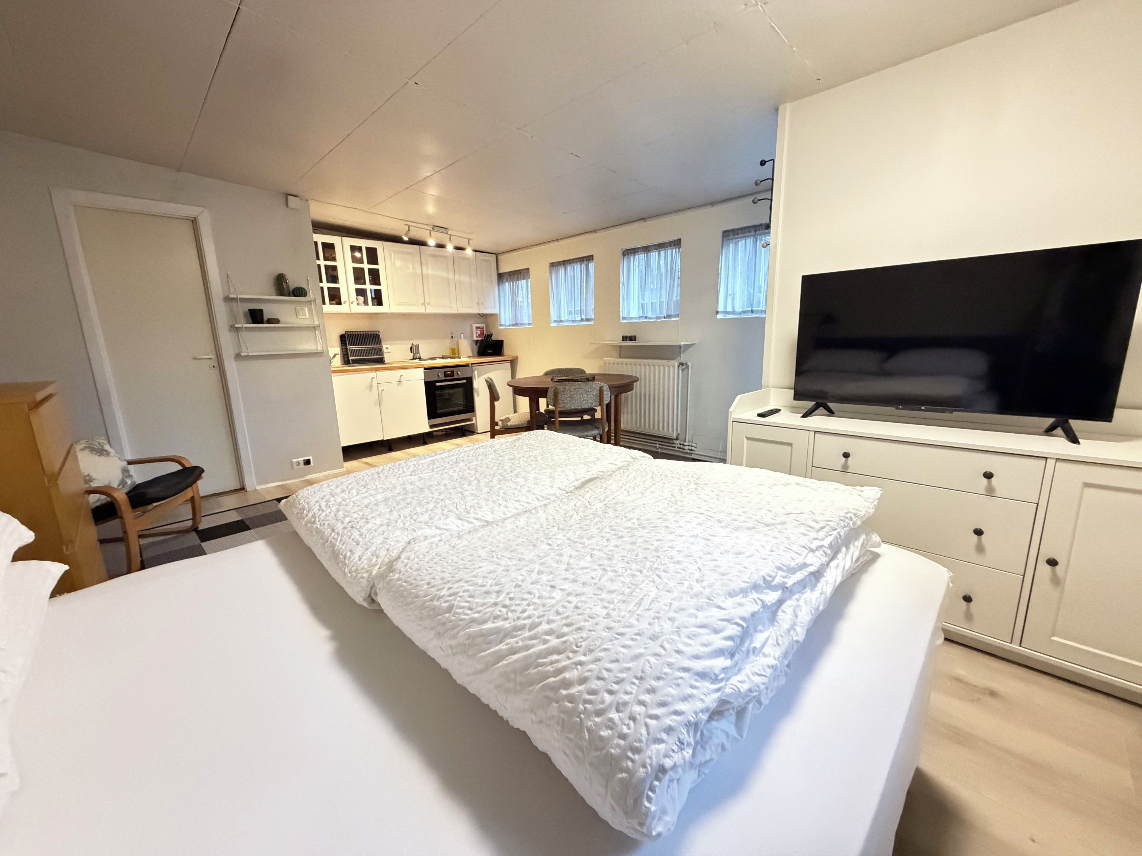 A hotel room with a bed, a TV, a kitchenette, and a dining area.