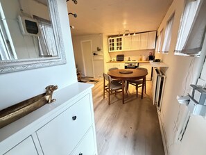 A compact kitchen with white cabinets, a wooden dining table, and a small refrigerator. - Cosy studio apartment in downtown Reykjavik (Reykjavík)