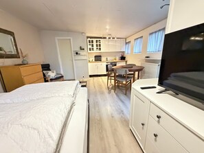 A compact room with a bed, a TV, a kitchenette, and a dining area. - Cosy studio apartment in downtown Reykjavik (Reykjavík)