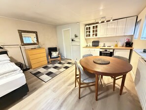 A compact living space with a bed, a small desk, a chair, a dining table, and a kitchenette. - Cosy studio apartment in downtown Reykjavik (Reykjavík)