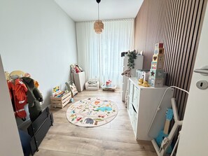 A child's playroom with a round rug, toys, and storage units. - Cosy and family friendly apartment in Reykjavik, Great location ! (Reykjavík)