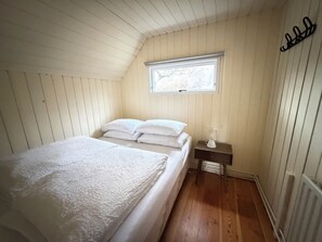 A room with a bed, a nightstand, a window, and a radiator. - Cosy cabin in Húsafell in Iceland, with Hot Tub. (Húsafell)
