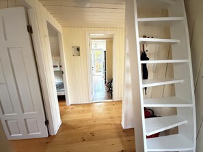 A hallway with wooden flooring, a white door, and a white shelving unit with shoes. - Cosy cabin in Húsafell in Iceland, with Hot Tub. (Húsafell)