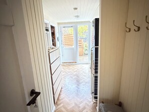 A hallway with a wooden door leading to a balcony, a radiator, and a small seating area.