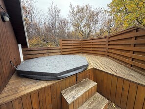 A hot tub with a wooden deck and a wooden fence. - Cosy cabin in Húsafell in Iceland, with Hot Tub. (Húsafell)
