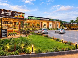 Un café et un restaurant avec une terrasse, un espace de stationnement et des jardins bien entretenus.