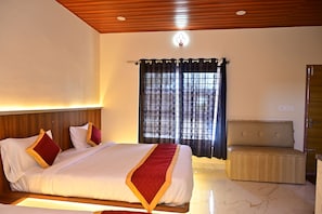 Quarto de hotel com cama, mesa de cabeceira e vista exterior através de uma janela com cortinas.