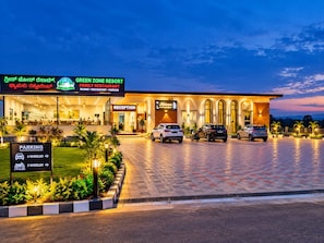 Um hotel com receção, placas de estacionamento e uma entrada bem iluminada.