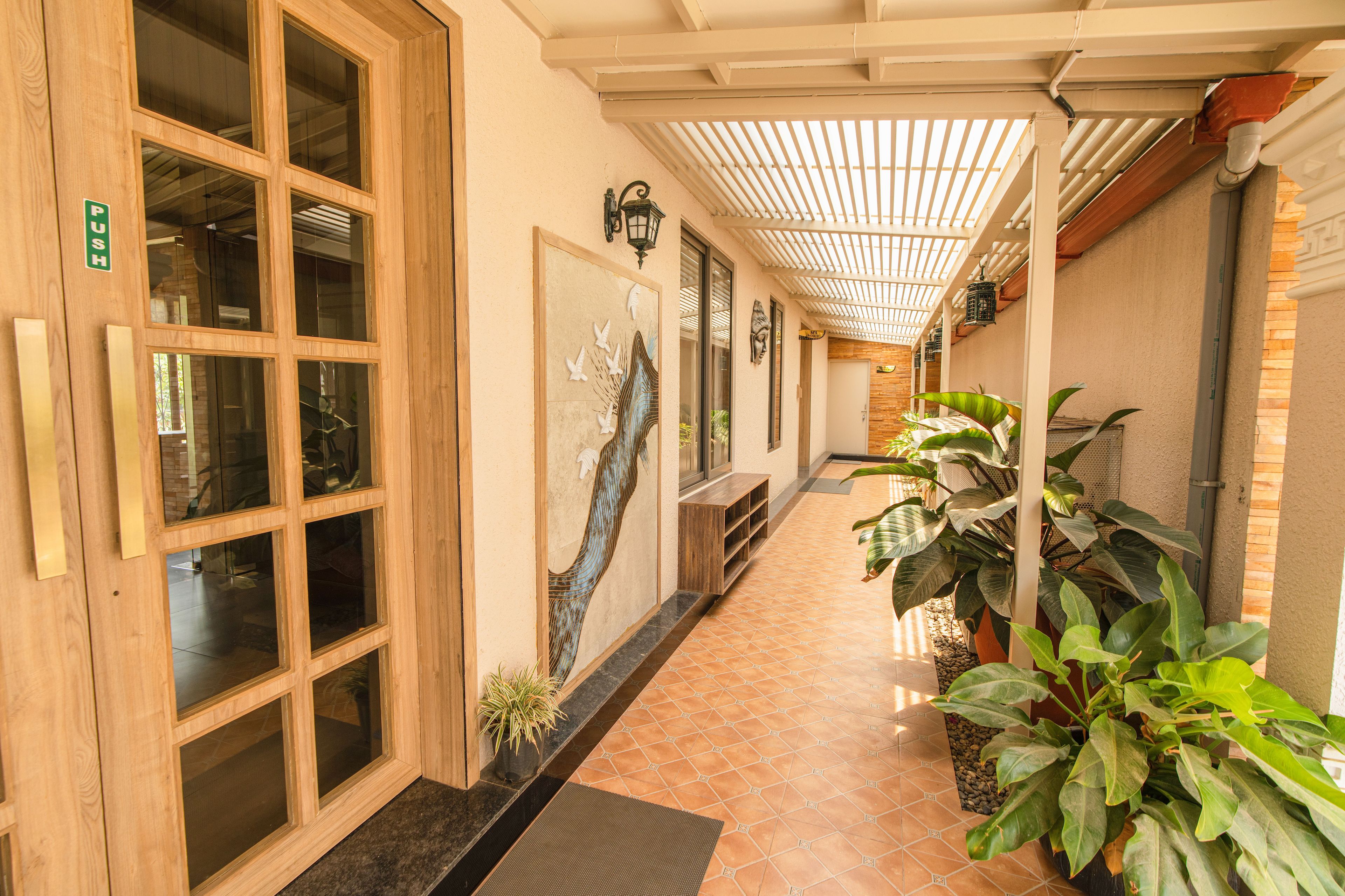 Un couloir avec des portes en bois, une œuvre d’art accrochée au mur et des plantes en pot.