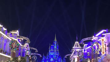 A large, ornate building with multiple spires and a central clock tower, surrounded by festive decorations and a crowd of people.