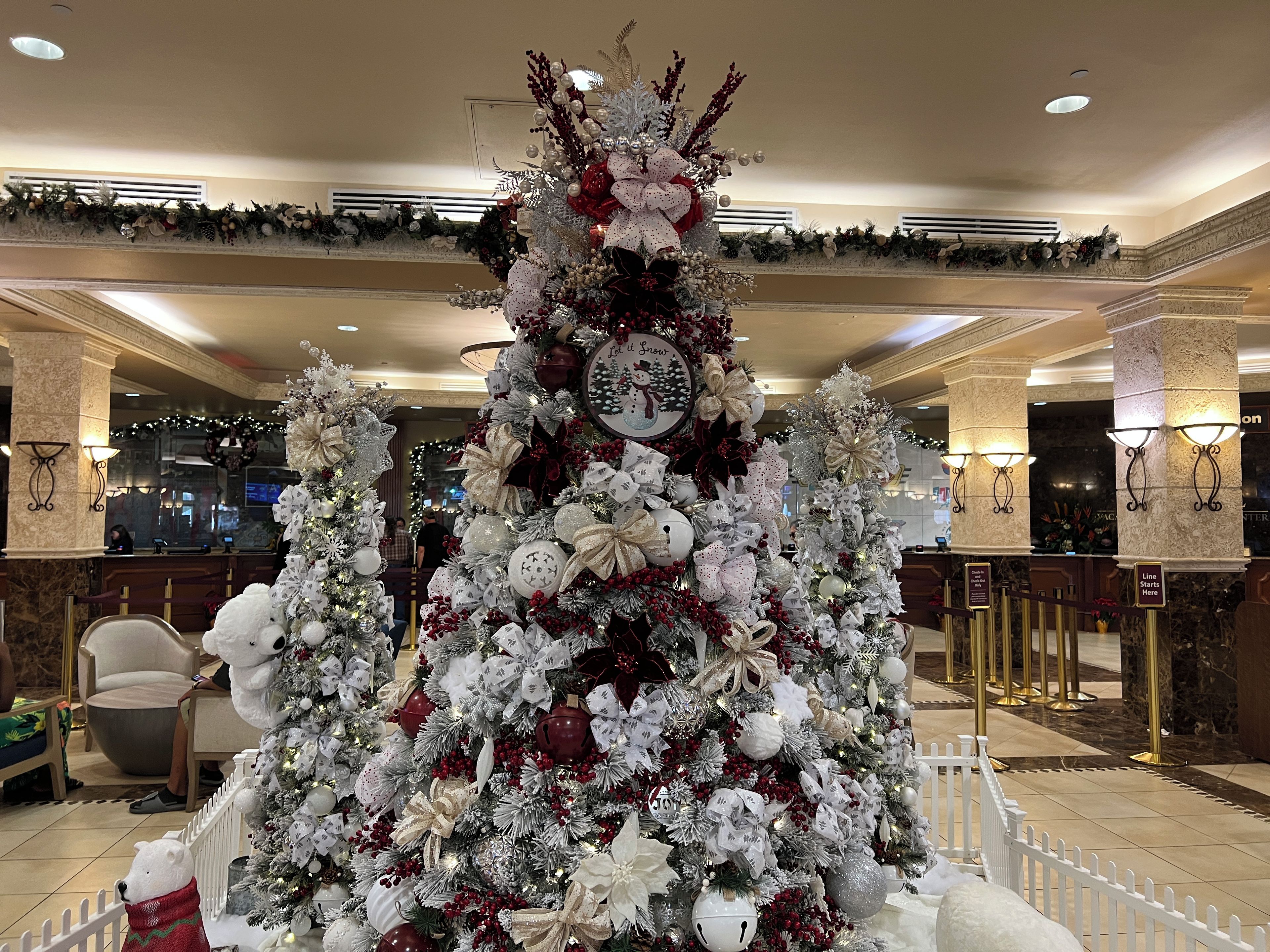 Un gran árbol de Navidad decorado en un vestíbulo con columnas de mármol y una recepción.