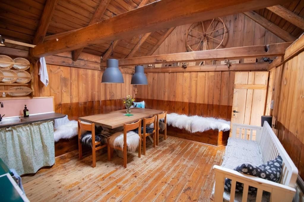 Interior rústico de madeira com uma mesa de jantar, cadeiras, um banco e um carrossel.