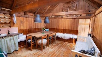 Interior rústico de madeira com uma mesa de jantar, cadeiras, um banco e um carrossel.