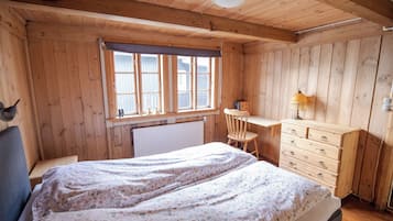 Una habitación de madera con una cama, un escritorio y una silla.