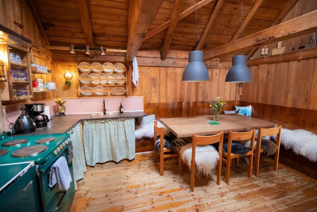 Eine rustikale Küche mit Holzwänden, einem grünen Herd und einem Esstisch mit Stühlen.