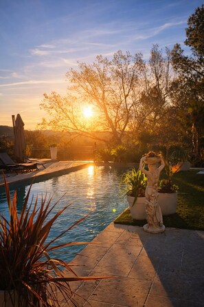 A swimming pool with a statue, surrounded by potted plants and a clear sky. - New Listing (Pertuis)