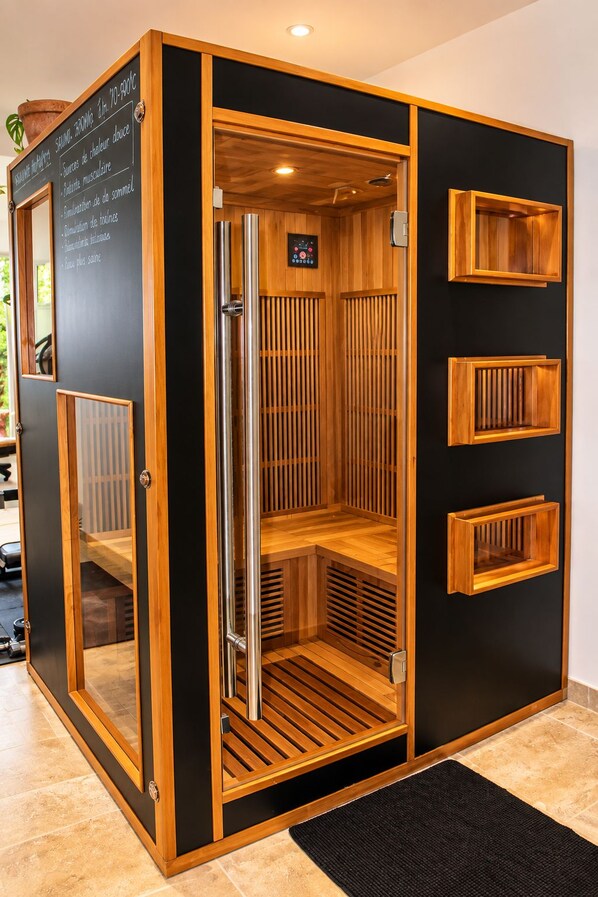 A sauna with a wooden interior, a control panel, and a black exterior. - New Listing (Pertuis)