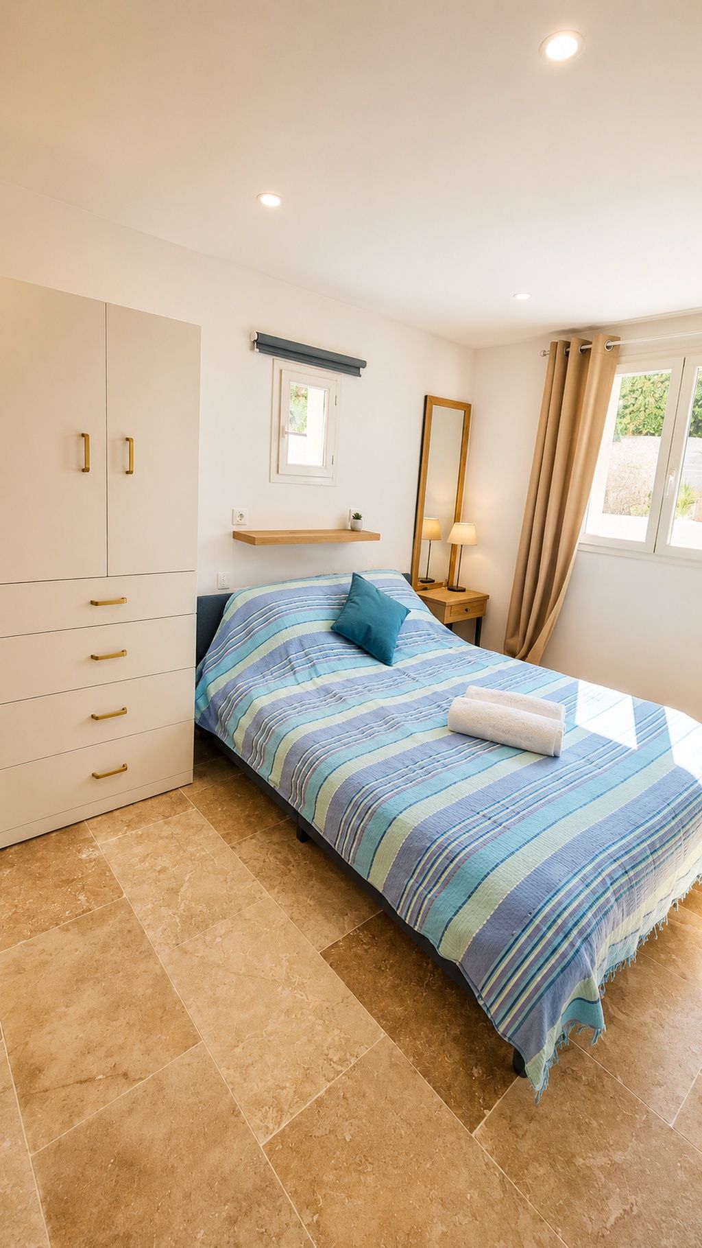 A bedroom with a bed, a wardrobe, a nightstand, a mirror, and a window with curtains.