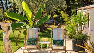 Two chairs with patterned cushions, a small table, and a statue in a garden setting.