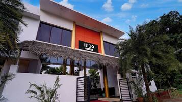 A modern hotel with a prominent 'HOTEL' sign, large windows, and a thatched roof entrance.