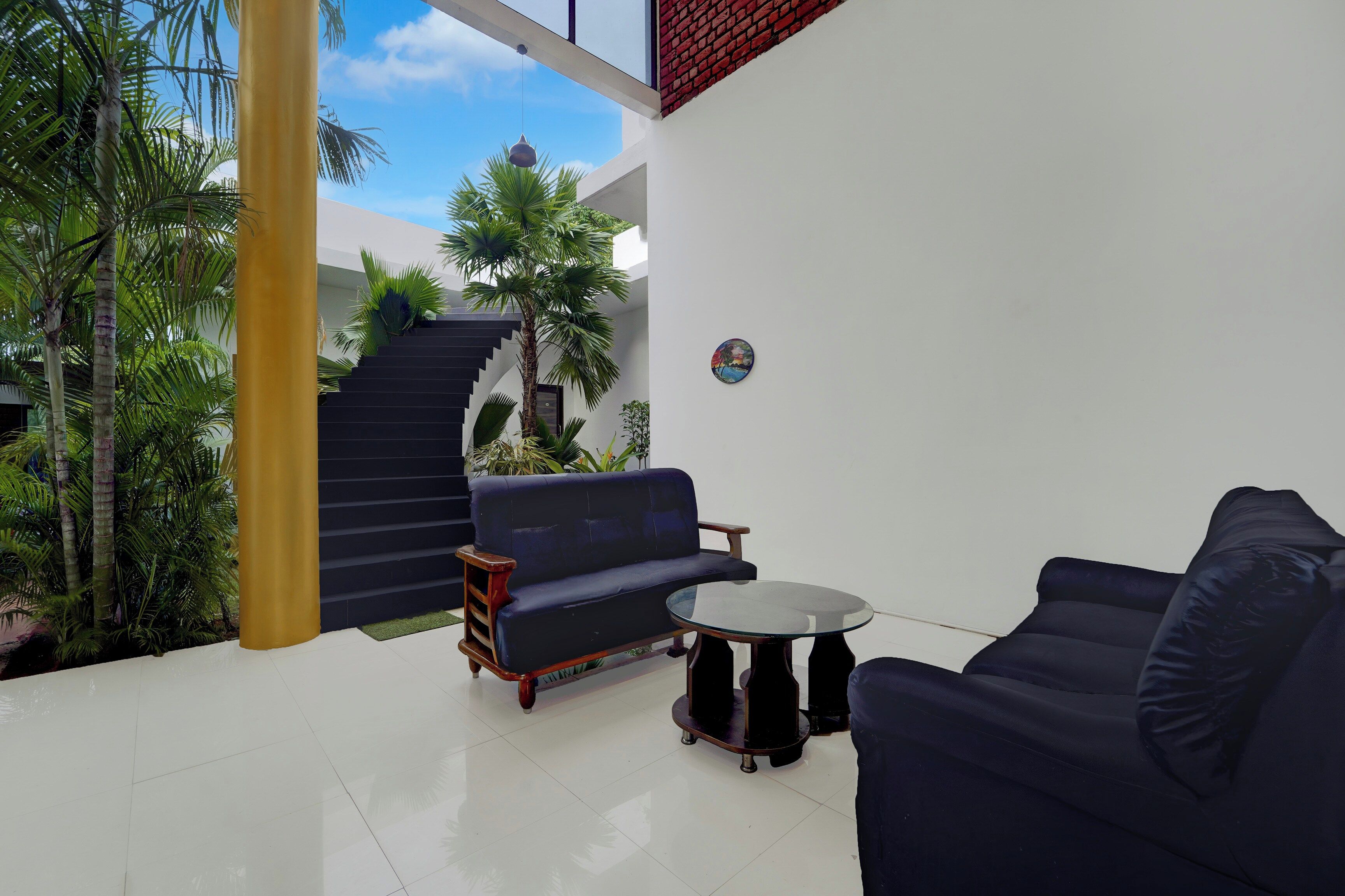 A modern outdoor seating area with a sofa and a small table, surrounded by plants and a staircase.