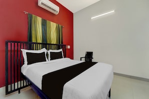 Ein Hotelzimmer mit einem Bett, einem Nachttisch, einer Klimaanlage und einem Fenster mit Vorhängen.